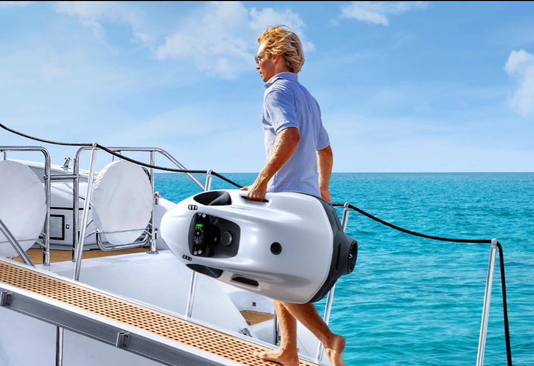 Yacht crew member carrying a Seabob along the side deck &mdash; routine pre-season movement to and from charging